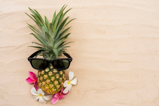 Foto ananas mit sonnenbrille am sandstrand für ihr urlaubshintergrunddesign