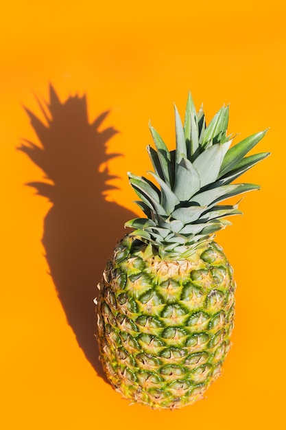 Ananas mit trendigem hartem Licht und orangefarbenem Hintergrund