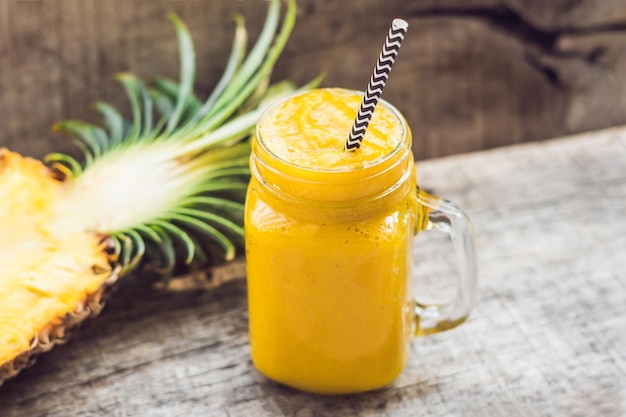 Ananas-Smoothie mit frischer Ananas auf Holztisch.