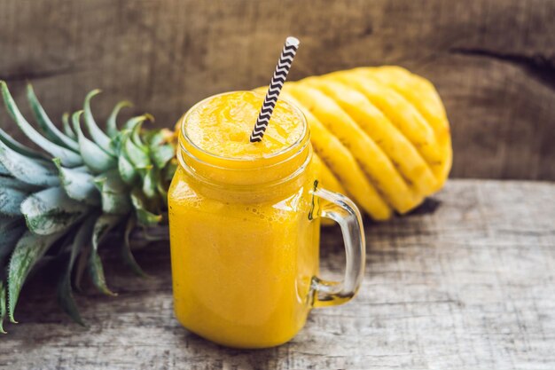 Ananas-Smoothie mit frischer Ananas auf Holztisch.