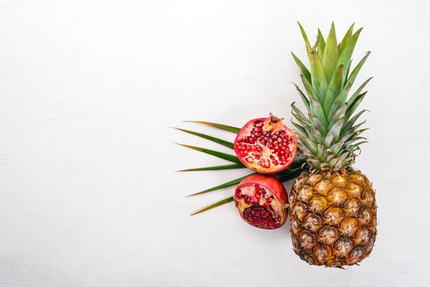 Ananas und Granatapfel Frisches Obst auf einem hölzernen Hintergrund Ansicht von oben Freier Platz für Text