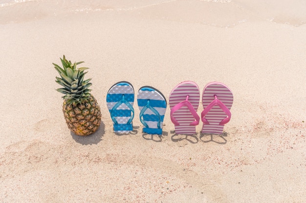 Ananas und Hausschuhe an einem tropischen Strand