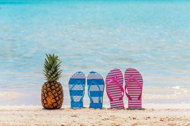 Ananas und Hausschuhe an einem tropischen Strand