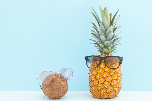 Ananas und Kokosnuss mit Sonnenbrille ruhen und Cocktail am Strand trinken Sommerurlaub
