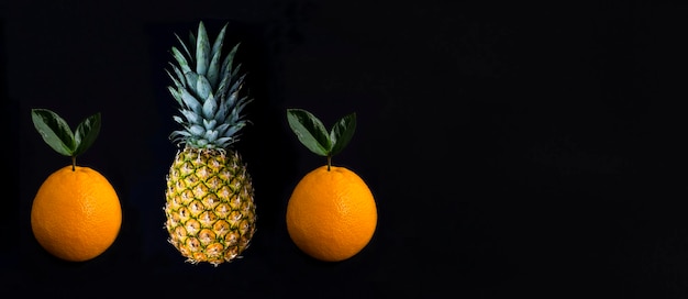 Ananas und Orange auf dem schwarzen Hintergrund Kopierbereich Closeup