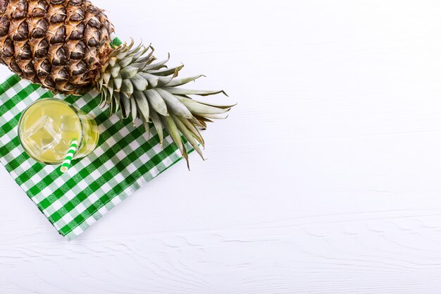 Ananascocktail mit Eis und grünem Stroh, auf einer weißen Tabelle. Sommerfruchtstimmung.