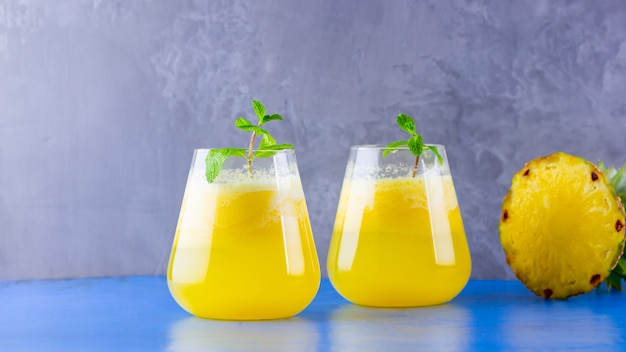 Ananassaft auf einem blauen grauen Hintergrund. Ananas-Smoothie. Sommergetränk