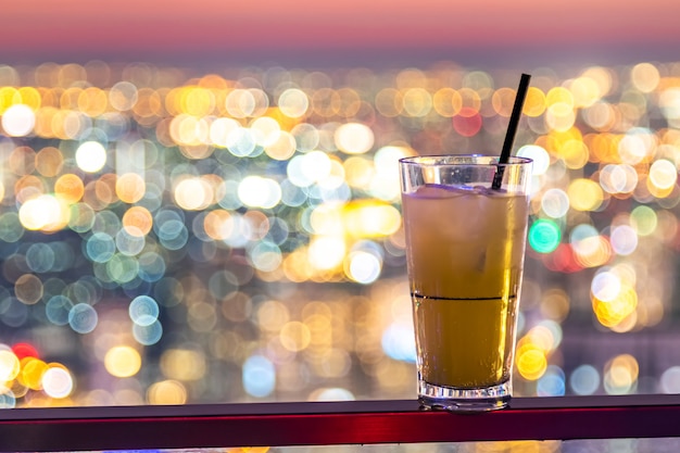 Ananassaft im Plastikglas- und Papierstroh auf dem Stadt bokeh Hintergrund.