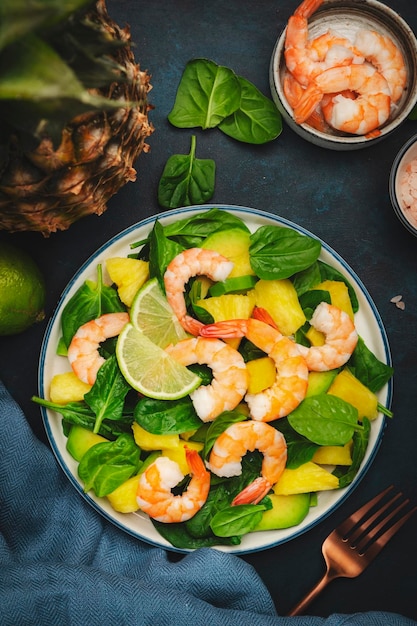 Ananassalat mit Garnelen, Spinat, Avocado und Limette auf blauem Stein Küchentisch Draufsicht Gesunde Ernährung, ausgewogene, saubere Ernährung, Gewichtsverlust Konzept