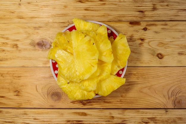 Ananasstücke in einem Teller auf Holztisch. Ansicht von oben