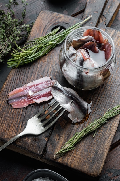 Anchova em conserva, numa tábua de madeira, na velha mesa de madeira escura