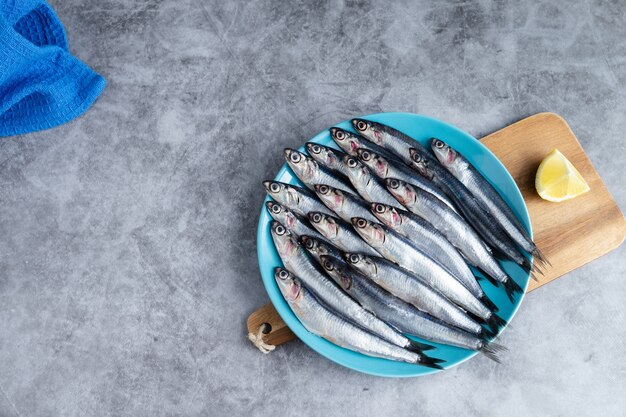 Anchovas inteiras em prato azul sobre fundo de mármore