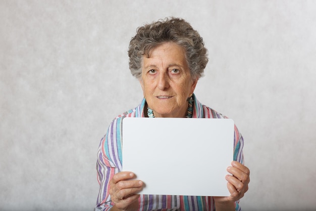 Anciana de entre 70 y 80 años con un papel. Espacio libre para un texto