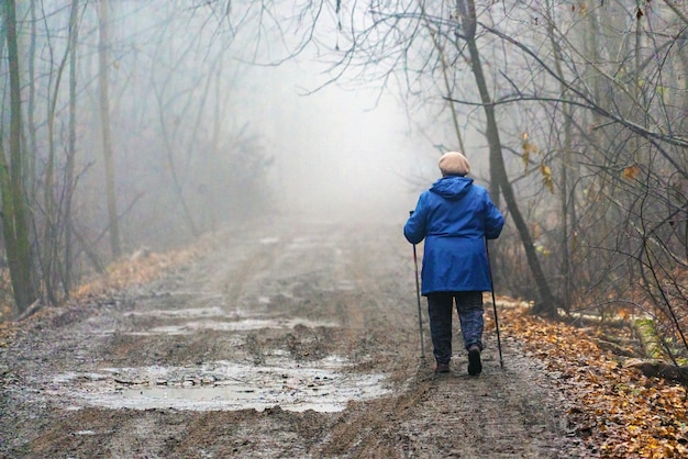 Foto una anciana se adentra en la niebla a lo largo de un camino sucio