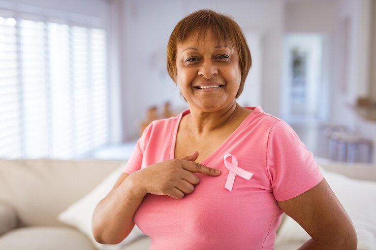Foto una anciana afroamericana señala la cinta de concienciación sobre el cáncer de mama en una camiseta rosa