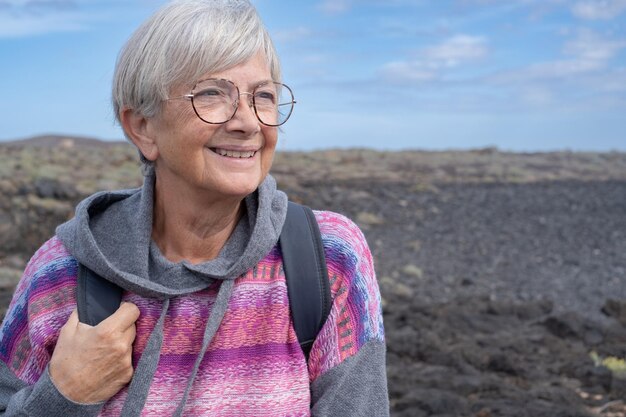 Anciana alegre en una caminata al aire libre con una mochila Una anciana en forma en una caminata disfrutando de la libertad de la aventura y unas vacaciones saludables
