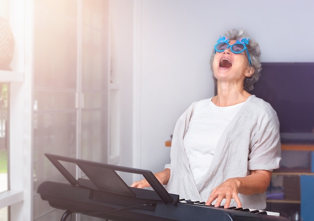 Anciana alegre tocando el piano, bailando y cantando