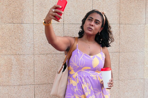 Anciana alegre tomando un selfie contra una pared.