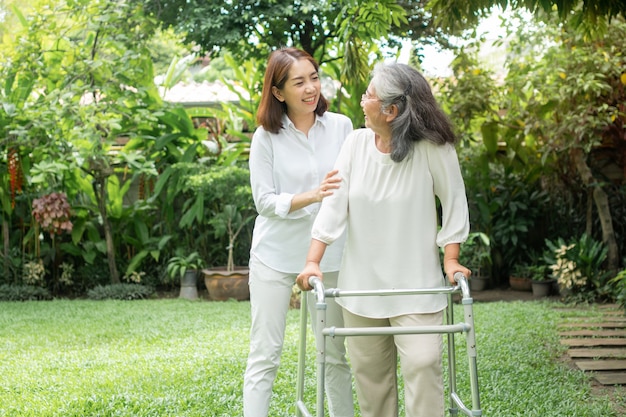 Una anciana anciana asiática usa un andador y camina en el patio trasero con su hija