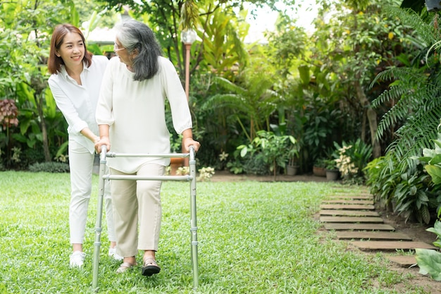 Una anciana anciana asiática usa un andador y camina en el patio trasero con su hija