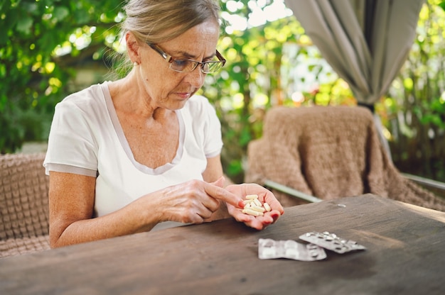 Anciana con anteojos tomando pastillas