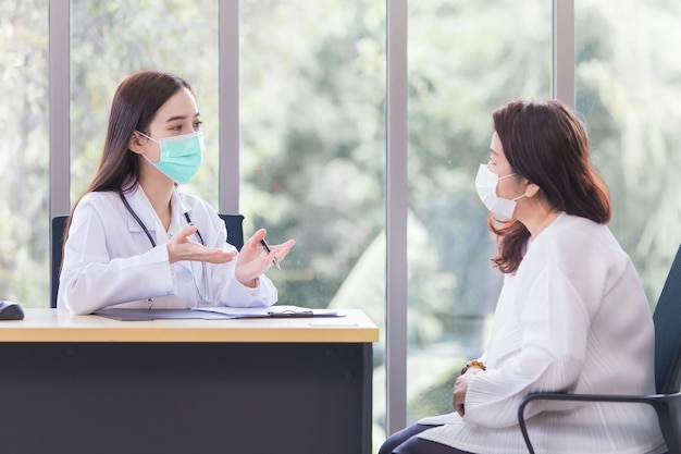 Una anciana asiática consulta con una doctora profesional sobre su síntoma o problema de salud.