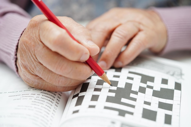 Foto anciana asiática jugando sudoku para practicar el entrenamiento cerebral para la prevención de la demencia alzheimer