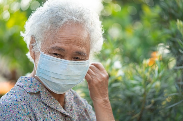 Anciana asiática con mascarilla fresca y feliz por la mañana en el parque