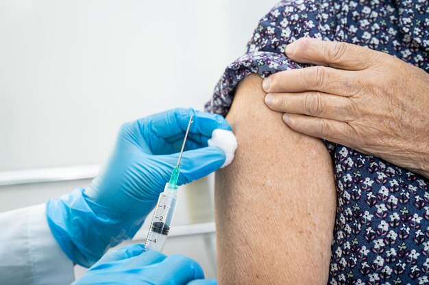Anciana asiática mayor que recibe la vacuna covid-19 o coronavirus por inyección médica.