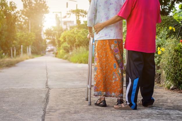 Anciana asiática de pie con las manos en un andador con la mano de la hija
