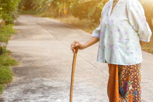 Anciana asiática de pie con las manos en un bastón