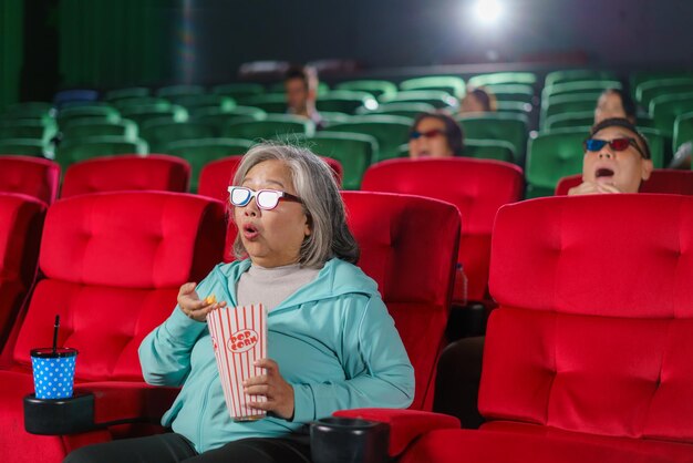 Foto una anciana asiática sorprendida por una película de terror en el cine