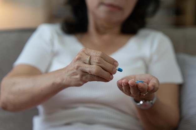 Anciana asiática tomando píldoras en casa Edad Medicina Salud y concepto de personas