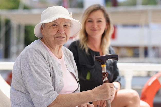 Anciana con bastón se sienta con su hija en la calle apoyo familiar y camina con jubilados