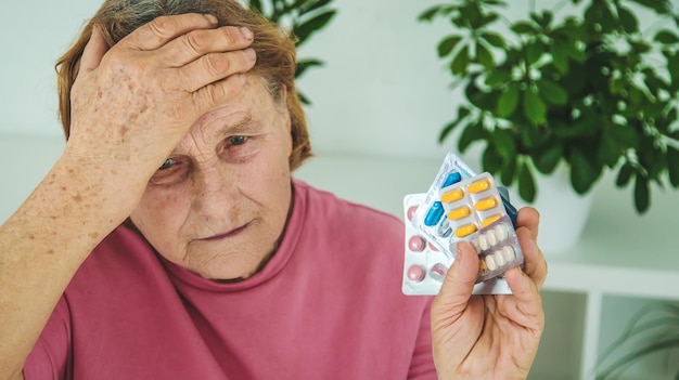 Una anciana bebe una pastilla para el dolor de cabeza Enfoque selectivo