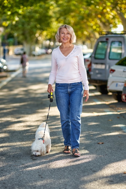 Anciana caminando con un perro al aire libre.