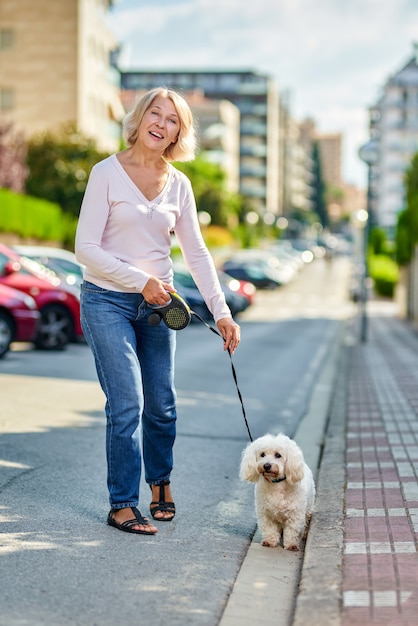 Anciana caminando con un perro al aire libre.