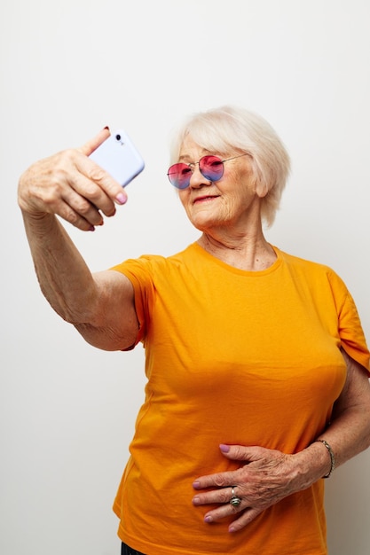 Anciana en una camiseta amarilla posando comunicación por teléfono emociones de primer plano