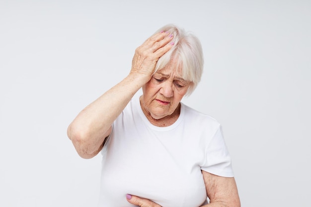 Anciana en una camiseta blanca dolor de cabeza problemas de salud vista recortada