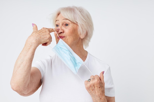 Anciana en camiseta casual y fondo claro de máscara médica