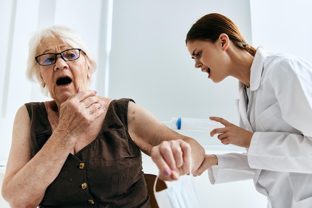 Una anciana en una cita con el médico en un hospital de jeringa grande