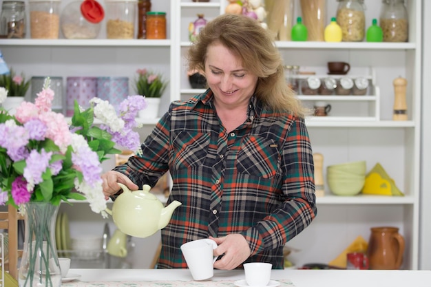 Anciana en la cocina con una tetera