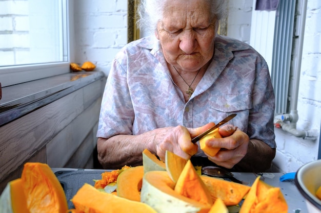 Anciana corta y pastillas calabaza amarilla cocinar sopa de calabaza jubilación vida enfoque selectivo