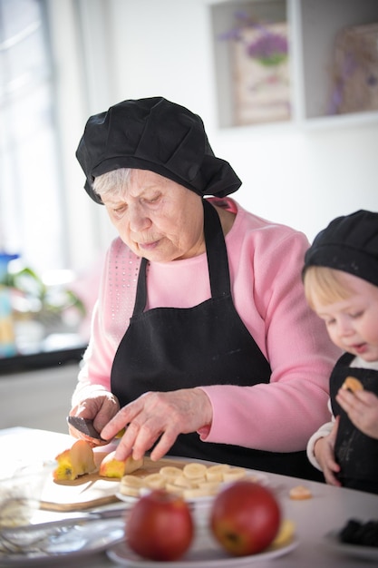 Una anciana cortando una manzana con una niña en la cocina