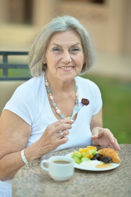 Anciana con desayuno y café afuera