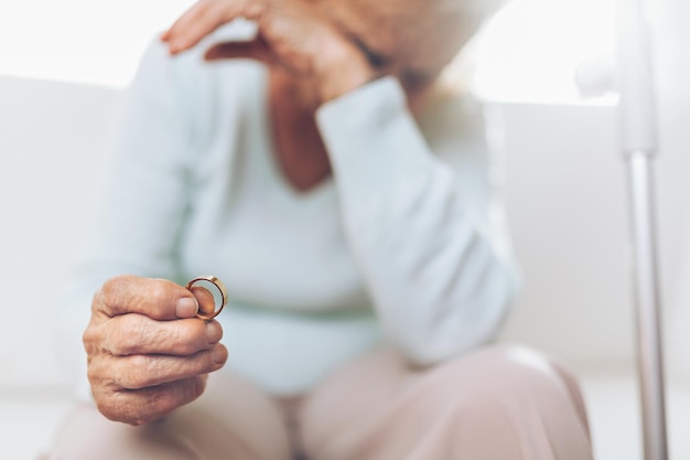 Anciana desconsolada sosteniendo un anillo de bodas