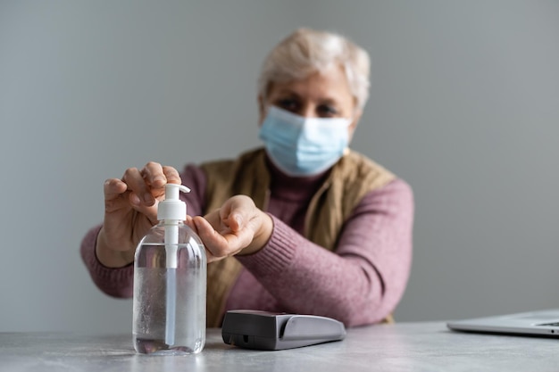 Anciana desinfectando sus manos con gel de alcohol.