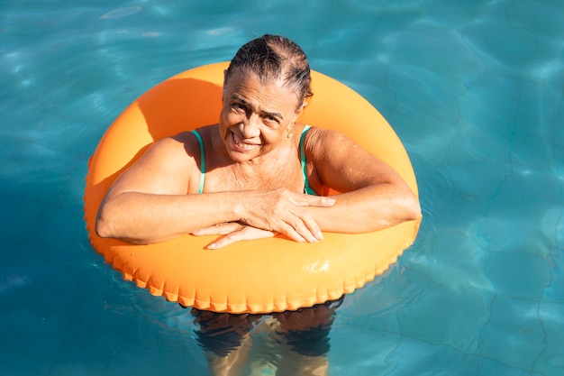 Anciana disfrutando de sus vacaciones en la piscina del hotel