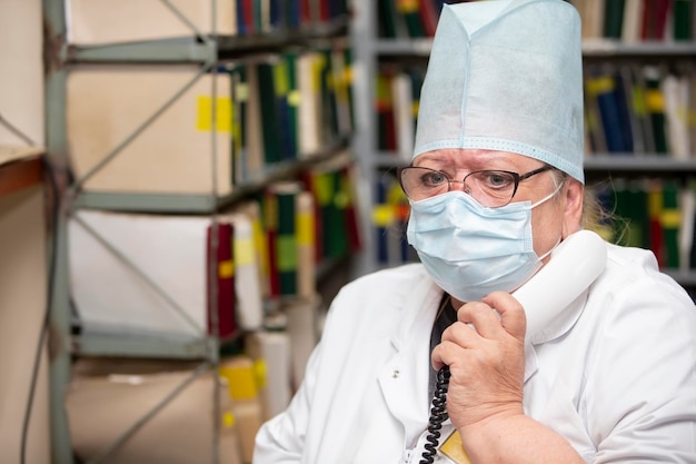 Una anciana doctora cansada que trabaja en la recepción de una clínica