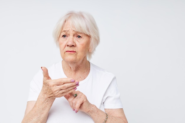 Anciana emocional en una camiseta blanca mala vista fondo claro